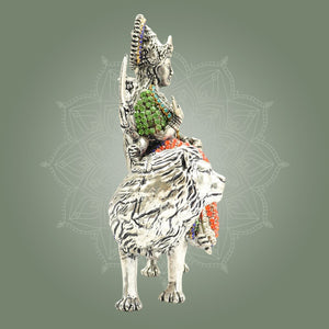 Decorative figurine of a seated figure on a creature with intricate detailing against a gray background